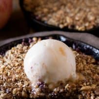 Apple and blackberry crumble in a mini cast iron skillet showing the filling of fresh blackberries and apple