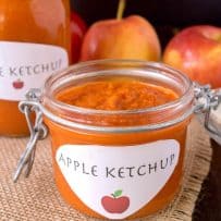A pop-top jar filled with curry ketchup with a homemade label with an apple