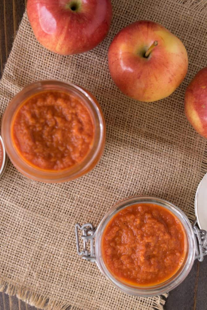 Overhead of jars of apple ketchup with red apples