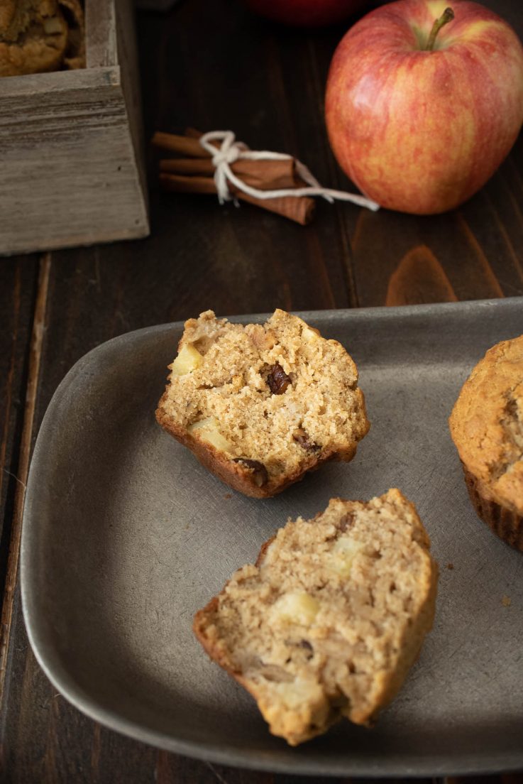 A muffin cut in half on a grey plate showing fresh apple and pecan inside