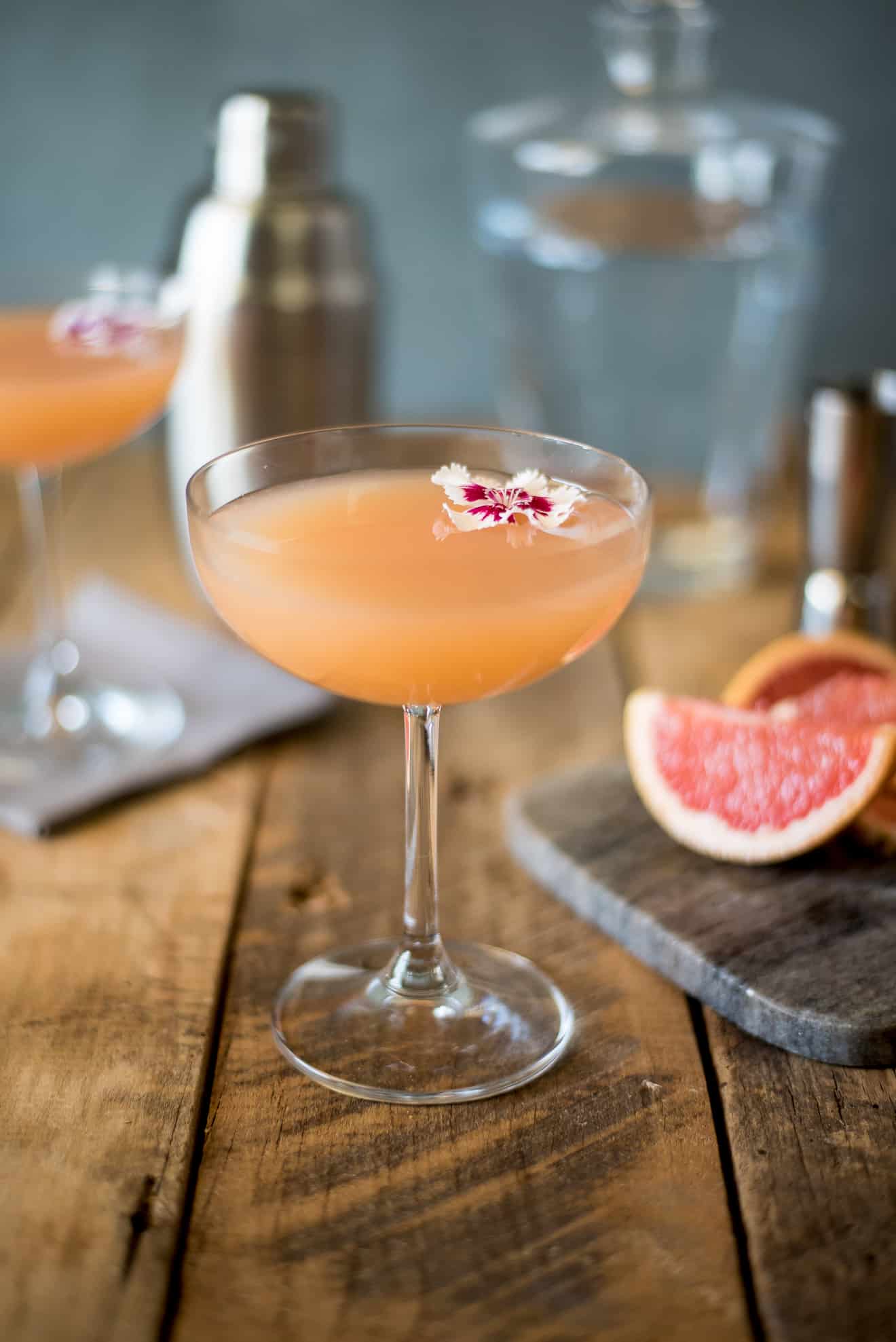 A stemmed glass of April Showers cocktail garnished with an edible flower