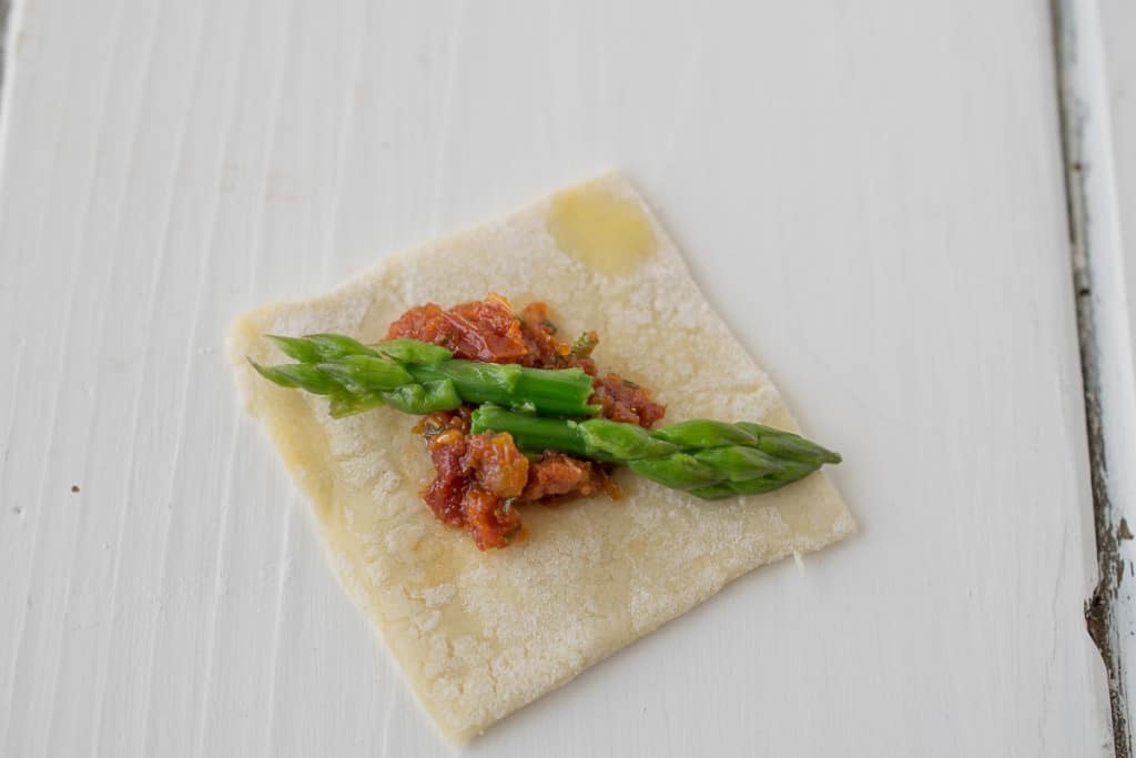 2 asparagus tips and sun-dried tomato on a square of puff pastry
