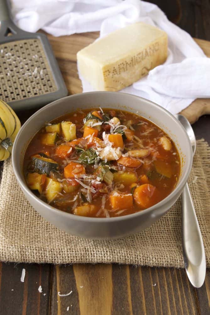 Autumn minestrone in a grey bowl topped with grated Parmesan cheese