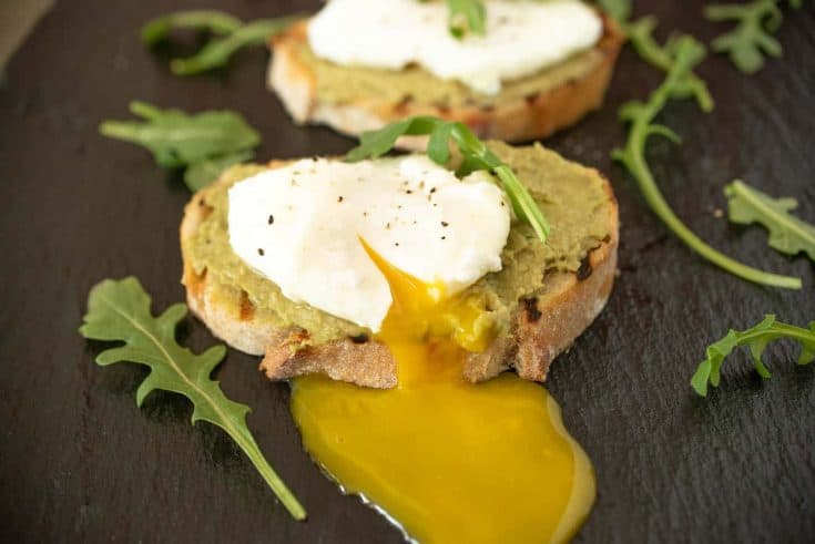 Avocado artichoke toast with a poach egg and runny yolk.