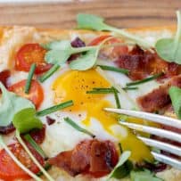 Cutting a runny yolk in the center of a breakfast tart with a fork