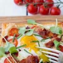Using a fork to break open a runny egg yolk on top of the tart