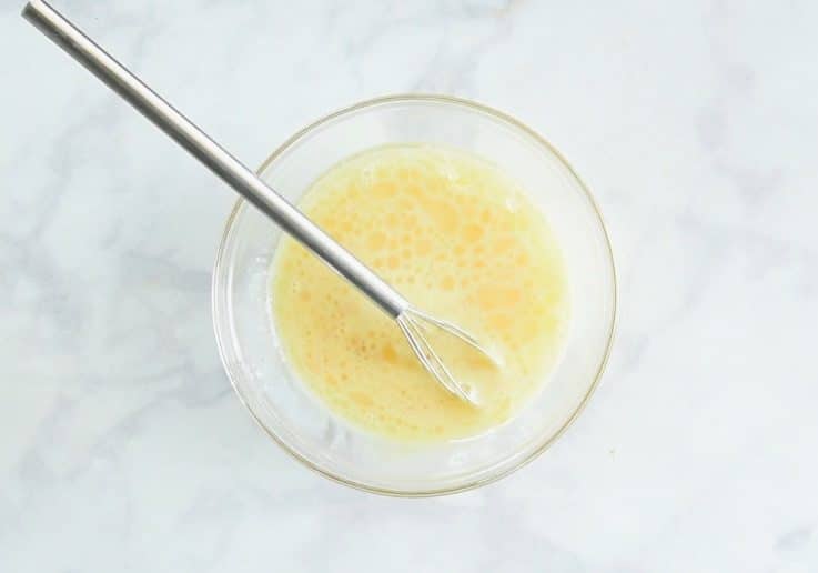 Eggs, milk and oil whisked in a glass bowl