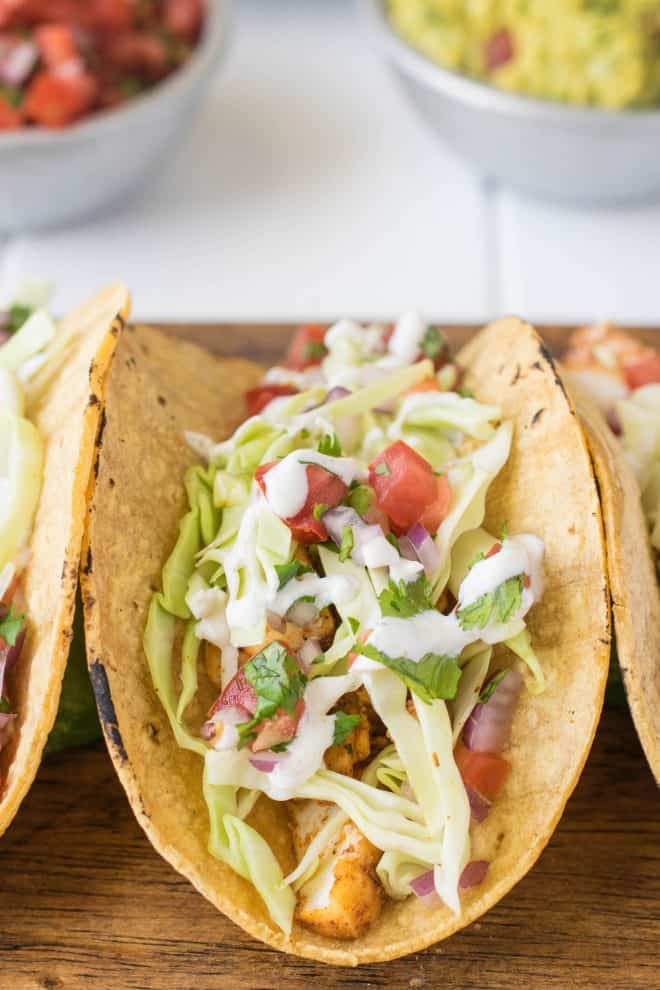 A healthy fish taco topped with pico de gallo, cabbage and crema