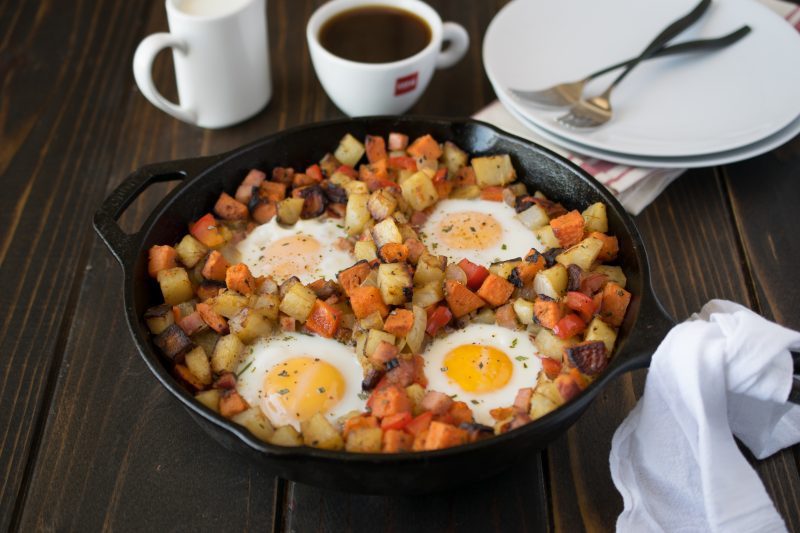 Potatoes are browned in a pan with 4 sunny side up eggs