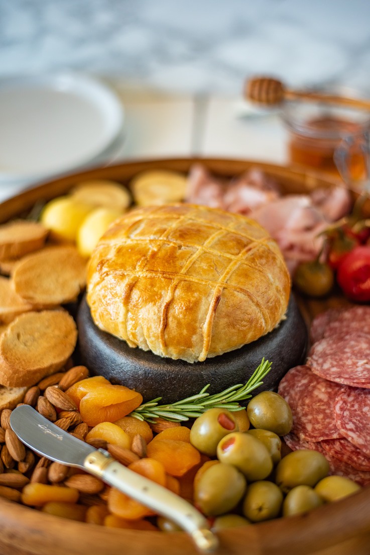 A closeup Baked brie and Black Forest ham in puff pastry on a charcuterie board with a knife