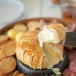 A cheesy, melted slice of Baked brie and Black Forest ham in puff pastry on a knife