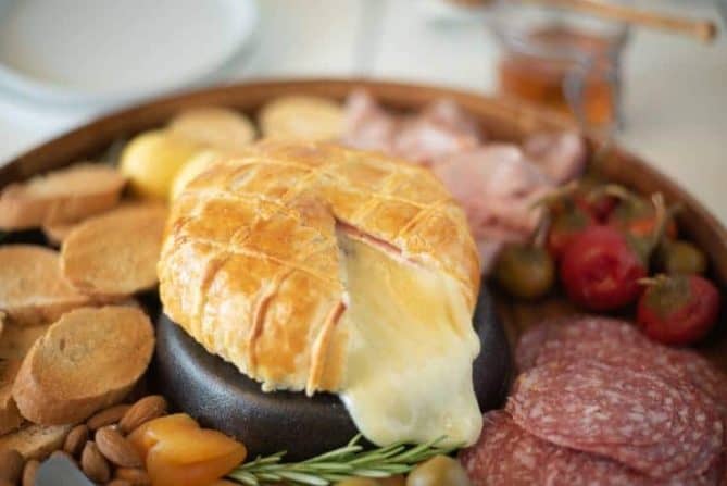 A cut open Baked Brie and Black Forest ham in puff pastry with lots of melted brie oozing out