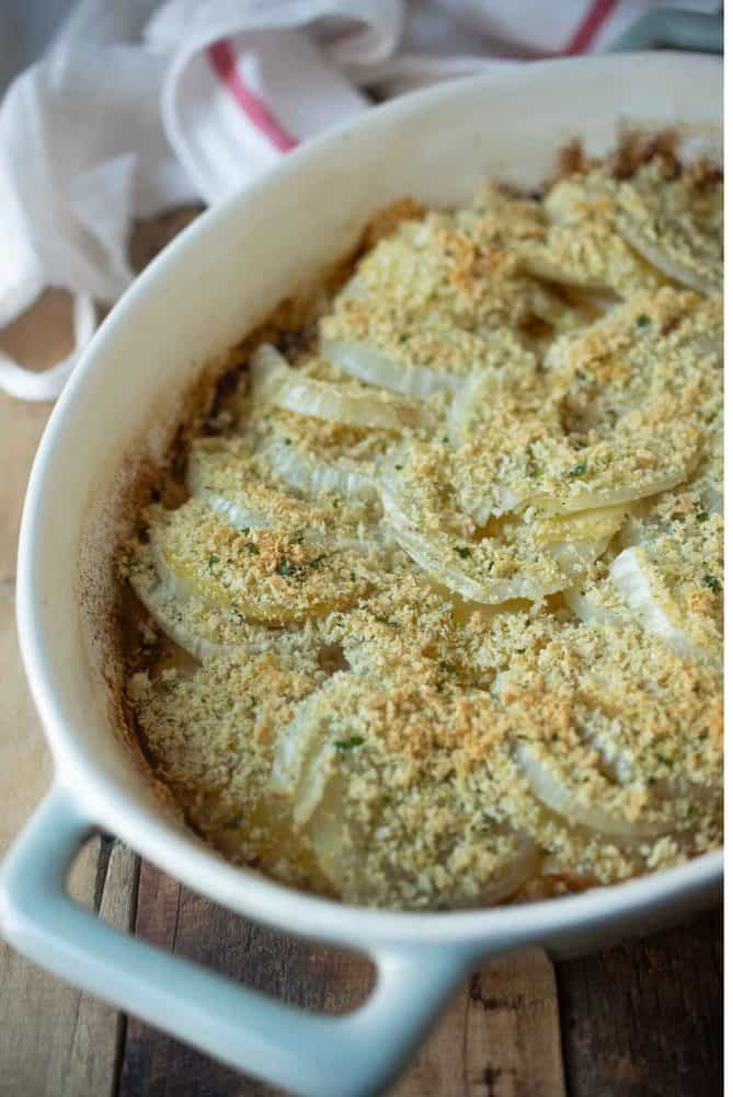 A closeup of sliced fennel and apple in a casserole dish topped with breadcrumbs
