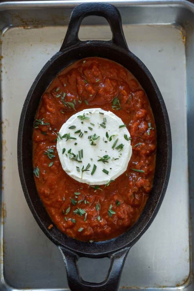 Baked herb goat cheese in marinara sauce going in the oven