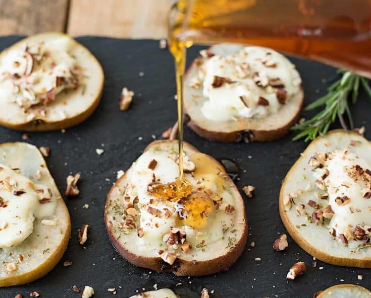 Pouring honey over baked pear slices with goat cheese and chopped pecans