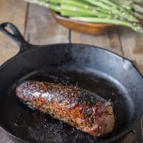 A whole pork tenderloin coated with sweet balsamic glaze in a cast iron skillet