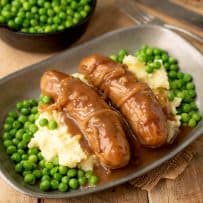 2 British bangers served with fresh peas, mash and onion gravy