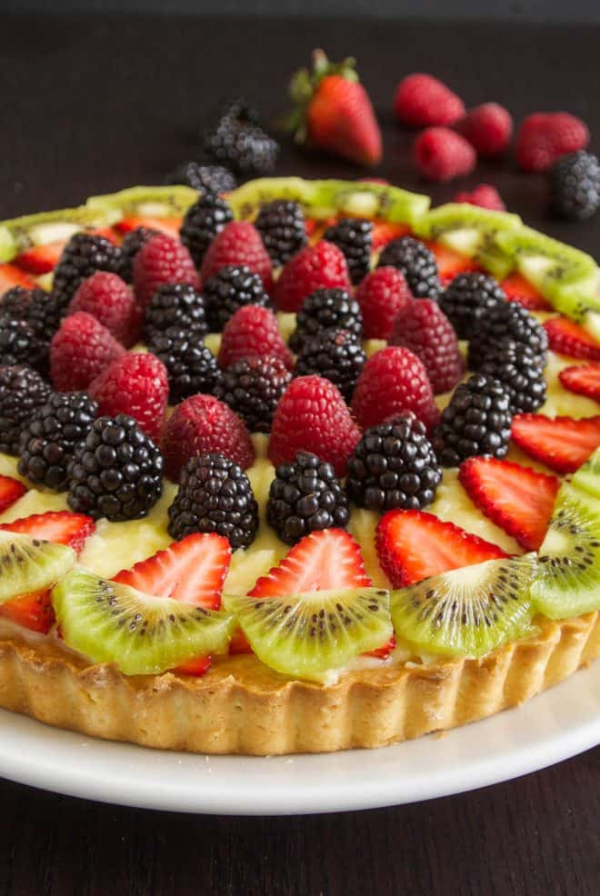 Red, black and green fruit on top of a berry custard tart