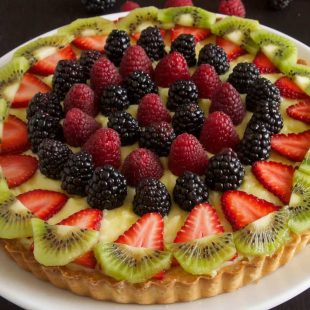 A custard tart decorated with colorful berries and kiwi