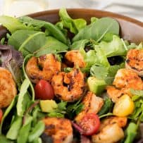 Blackened shrimp in a salad with cherry tomatoes and avocado and lettuce