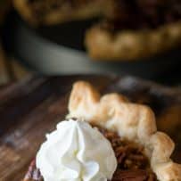 Layers of pecans in a pecan pie slice topped with whipped cream