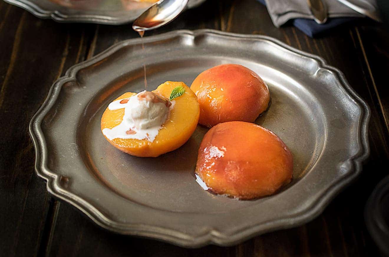 Drizzling bourbon sauce onto peach halves