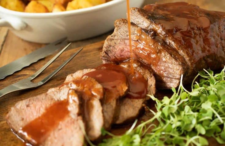 Sliced Tri tip getting drizzled with barbecue sauce