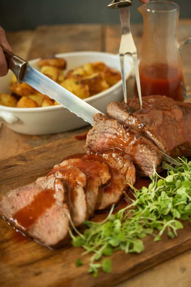 Carving slices of the Tri tip on a board with micro greens