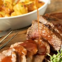 Barbecue sauce being drizzled over juicy Braised Tri tip
