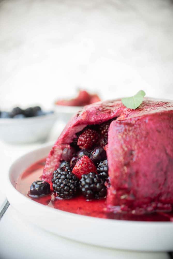 Summer bread pudding viewed from the side showing the bread cut open with berries inside
