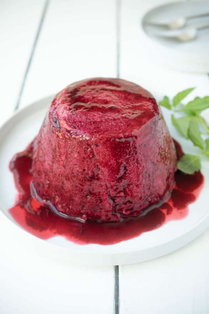 A mold of white bread covered in berry juice on a white plate