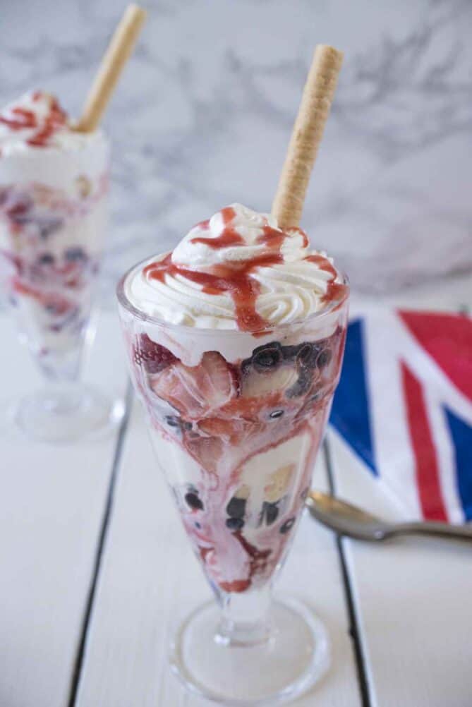 A rolled wafer cookie in a sundae topped with cream and homemade strawberry sauce