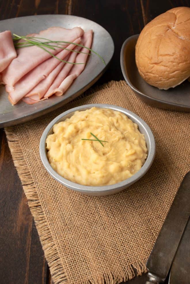 A silver bowl with Pease Pudding, ham and a bread roll