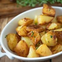 Browned, roasted potatoes in a white oval serving dish