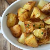A closeup of British roast potatoes garnished with fresh parsley