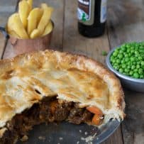 A steak and ale pie with a piece cut showing the chunky filling