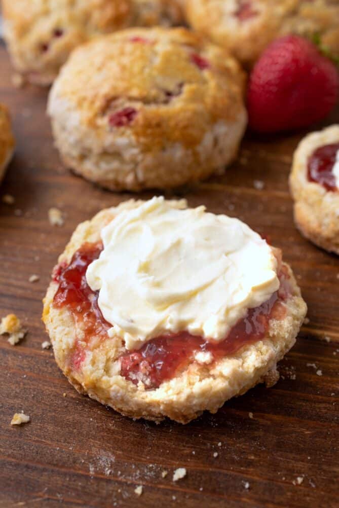 The bottom half of a scone topped with jam and clotted cream