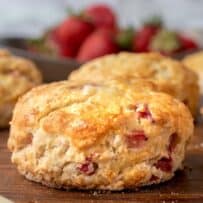 A British scone made with fresh strawberries on a board with a knife.