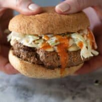 Holding a burger with hot sauce dripping