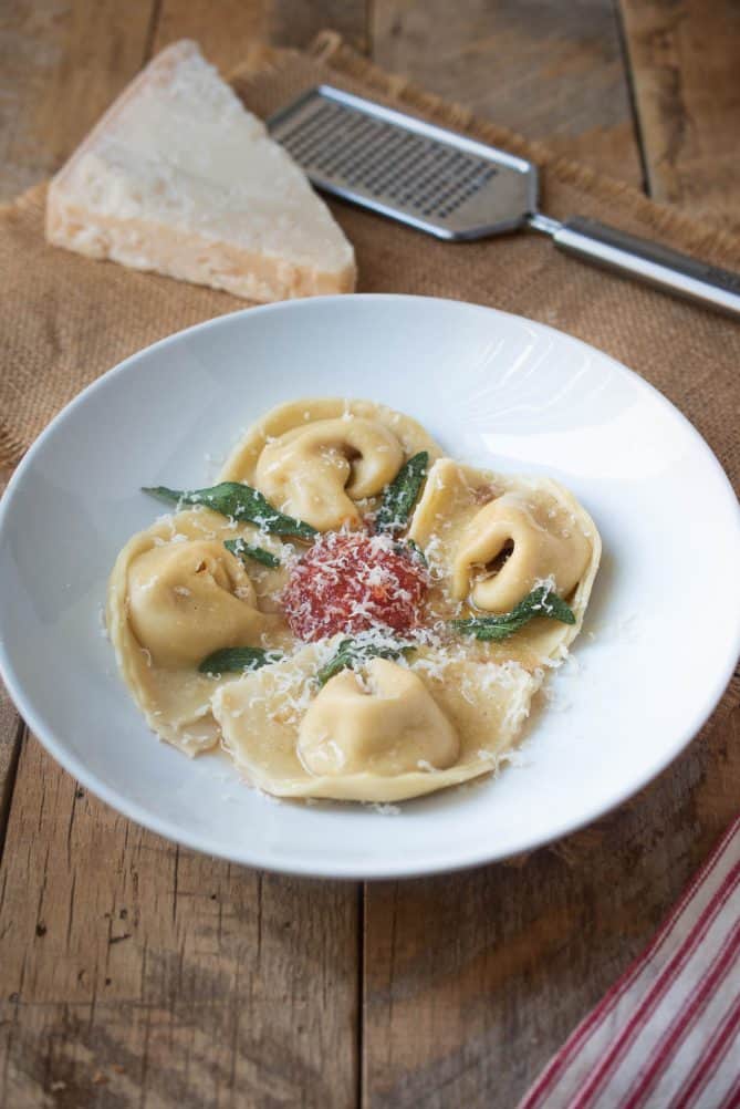 Grated parmesan cheese lightly covering butternut squash filled pasta with fresh sage leaves