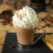 A cafe mochachino in a glass mug topped with whipped cream
