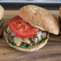 A closeup showing the melted cheese and tomato on a wheat bun