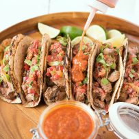 Carne asada tacos being topped with bbq sauce