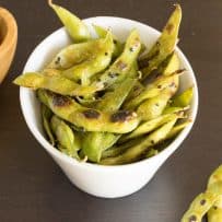 Cooked edamame in a bowl topped with togarashi spice and black sesame seeds