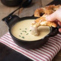 Dipping a piece of soft pretzel in a bowl of beer cheese soup