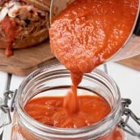 BBQ sauce being poured onto a glass storage jar