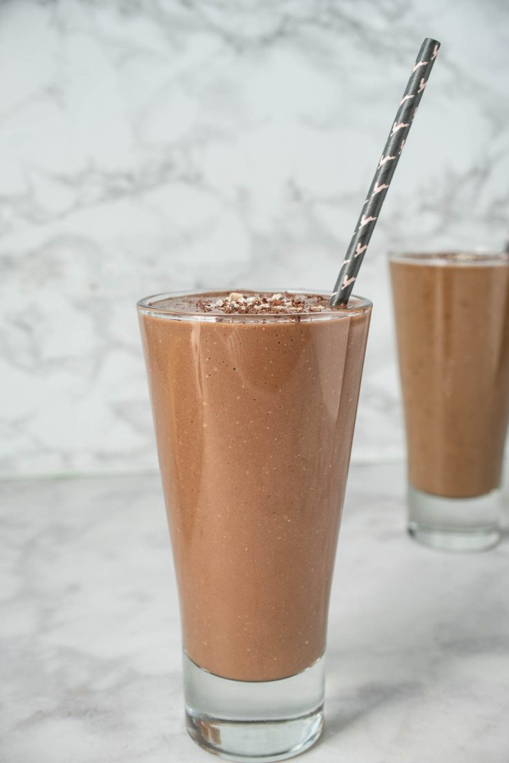 A side view of chocolate matcha breakfast smoothie with a straw