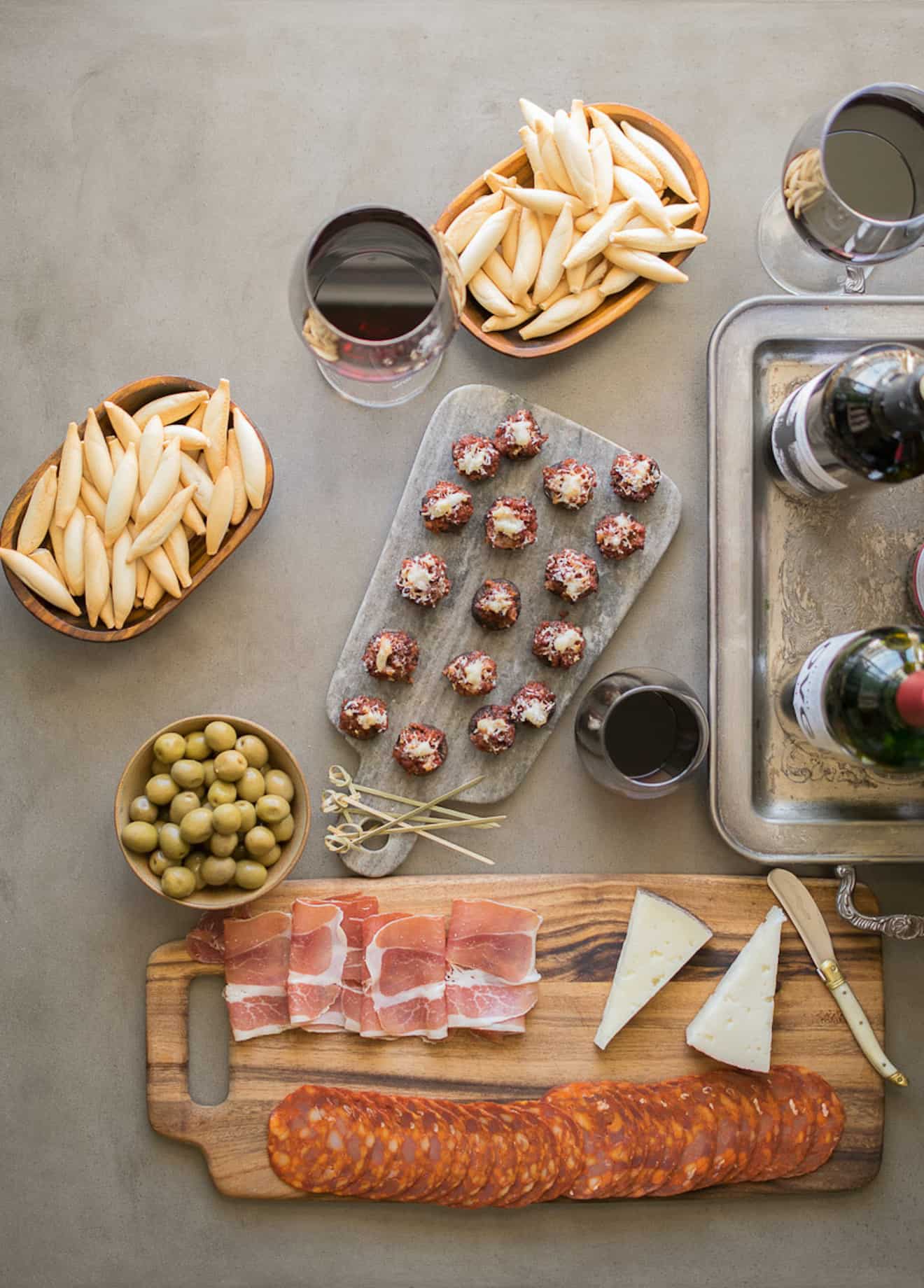 An array of tapas, chorizo stuffed mushrooms, meats, cheeses, crackers and wine
