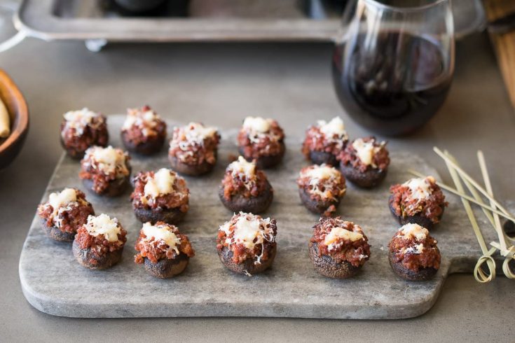 A platter of chorizo stuffed mushrooms with a glass of red wine