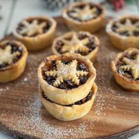 Christmas Sweet Mince Pies on a wood board dusted with powdered sugar
